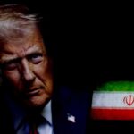 Close-up portrait of a man with a serious expression, with the Iranian flag in the background