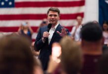 Texas Democrat’s Faith Remarks Spark Backlash Speaker in a suit addressing an audience with a microphone