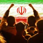 Declared Dead, Now Seen Publicly Crowd of people raising their fists in front of the Iranian flag