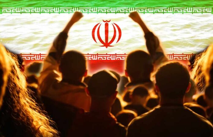 Crowd of people raising their fists in front of the Iranian flag
