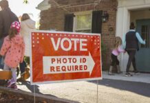 Polls Reveal Democratic Divide On Elections Red voting sign with arrow near people entering a polling place