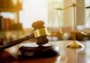 Judge's gavel on a block with scales of justice in the background