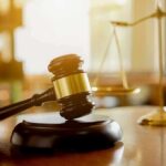 Judge's gavel on a block with scales of justice in the background