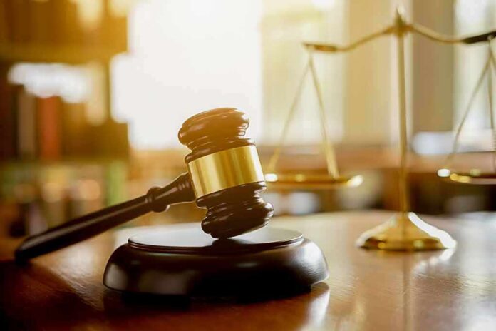 shutterstock_1075819205 Judge's gavel on a block with scales of justice in the background