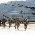 Evacuate Now: Middle East Routes Collapse Soldiers disembark and walk past a large military helicopter