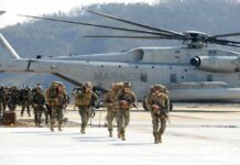 Evacuate Now: Middle East Routes Collapse Soldiers disembark and walk past a large military helicopter