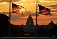 U.S. Capitol silhouette with American flags at sunset