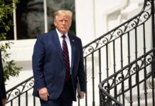 Trump Reshapes Childhood Vaccine Recommendations Man in navy suit standing by ornate staircase