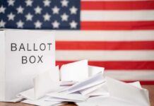 Ballot box with papers in front of an American flag