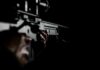 Close-up of hands holding a rifle in low light