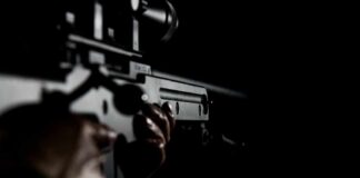 Close-up of hands holding a rifle in low light