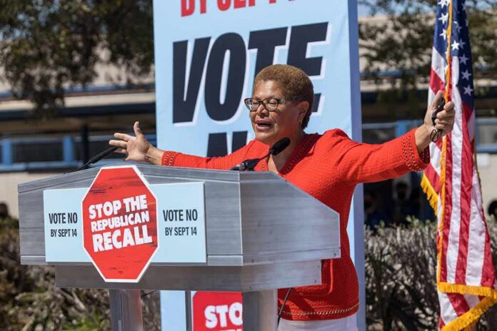 Speaker at outdoor rally behind podium with vote signs