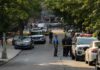 Police officers secure a residential street with patrol cars and yellow tape
