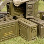 Stack of green military ammunition boxes on grass
