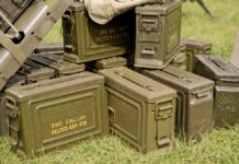 Stack of green military ammunition boxes on grass