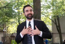 Man in suit speaking with hands on chest outdoors