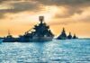Naval warships anchored in a harbor at sunset