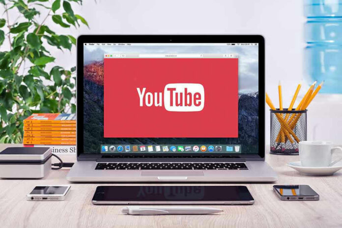 293731811 YouTube logo on a laptop screen on desk.
