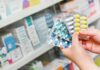 Dem Denial Collides With Costly Receipts Hands holding blister packs of assorted pills in a pharmacy