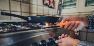 Person lighting a gas stove under a frying pan