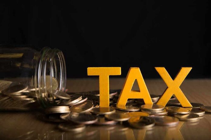 shutterstock_1181145091 Yellow TAX letters among coins and a tipped jar