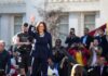 Foreign Influence Fears Hit Newsom, Harris Kamala Harris waves on stage at an outdoor event; Povilas Vanagas is present among the crowd