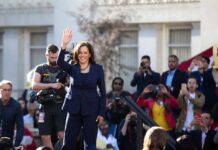 Foreign Influence Fears Hit Newsom, Harris Kamala Harris waves on stage at an outdoor event; Povilas Vanagas is present among the crowd