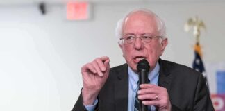 Bernie Sanders speaking into a microphone at an indoor event