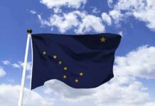 Abuse Allegations Roil Alaska Senate Race Alaska state flag waving on a pole against a blue sky