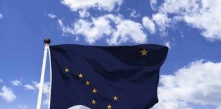 Alaska state flag waving on a pole against a blue sky