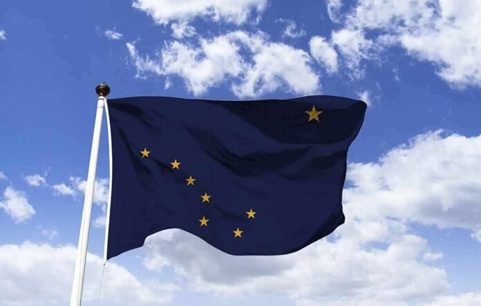Alaska state flag waving on a pole against a blue sky