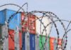 Razor wire fence in front of stacked shipping containers