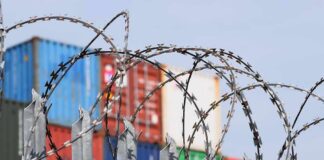 Razor wire fence in front of stacked shipping containers