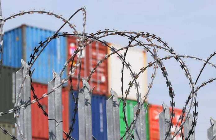 Razor wire fence in front of stacked shipping containers