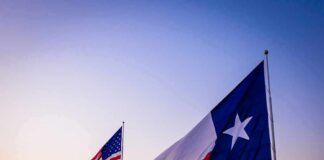Texas and United States flags waving at sunset