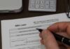 Hand holding pen over SBA loan application form