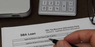Hand holding pen over SBA loan application form