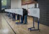 Feds Defy Newsom – Investigations Roll On Voters at polling booths in a gymnasium