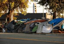 Street encampment with tarps and makeshift tents by roadside