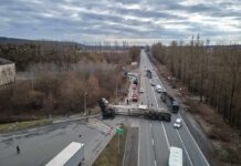 Overturned semi-trailer blocks highway at rural intersection