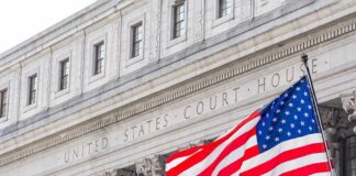 American flag waves in front of a United States courthouse facade