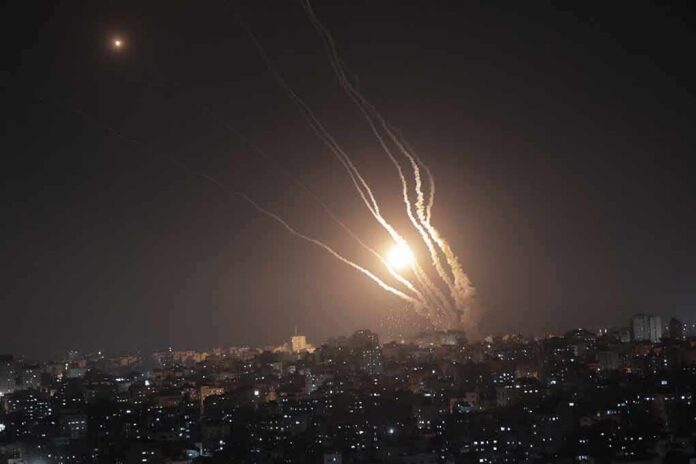 shutterstock_2301205711 Night sky above a city with multiple rockets arcing and bright explosions