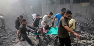 Rescuers carry an injured person on a stretcher through rubble