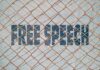 Rusty chain-link fence over bold text on a wall