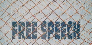 Rusty chain-link fence over bold text on a wall