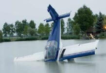 Engine Dies Midair — Congressman Hits Water A submerged airplane partially in a lake with trees in the background