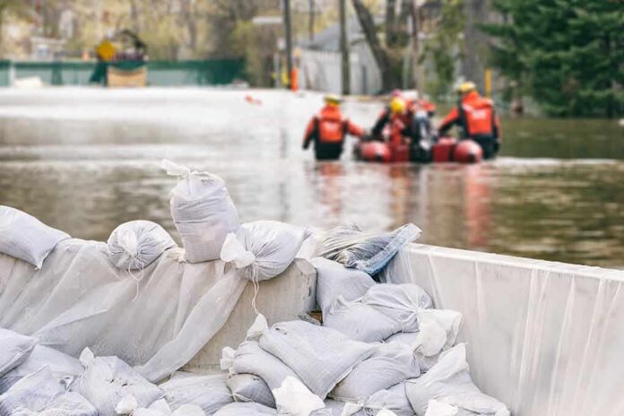 shutterstock_705371167 Sandbags stacked near a flooded street with rescue workers in a boat