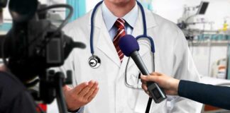 Doctor being interviewed with microphones in a hospital