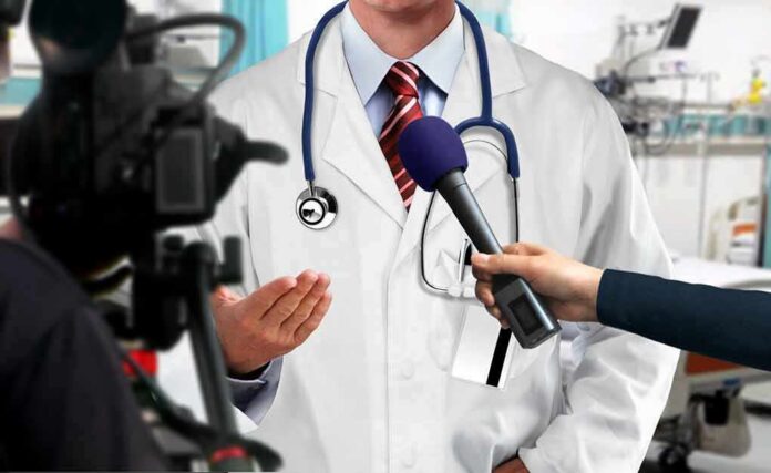 Doctor being interviewed with microphones in a hospital