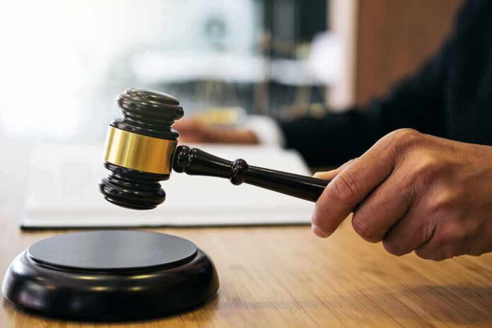 shutterstock_1023698749-1 Judge's hand holding a gavel over a sound block